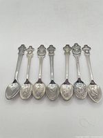Seven Rolex Bucherer souvenir teaspoons laid out