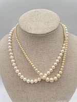 Both pearl necklaces displayed on bust showing uniform and graduated strands