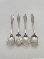 Four sterling silver teaspoons aligned bowl-up showing overall design and size