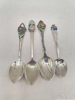 Four sterling souvenir spoons laid out