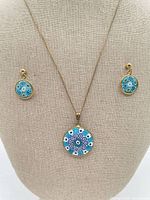 Full view of necklace and earrings on display stand