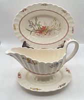 Gravy boat on under plate with oval serving bowl in background