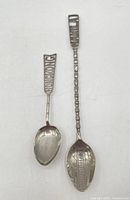 Full view of both sterling souvenir spoons showing relative sizes and designs