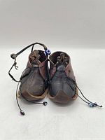 Front view of pair showing curled toe design, laces with beads