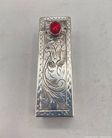 Closed lipstick case showing engraved design and red cabochon