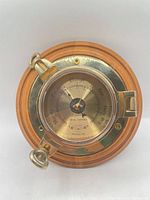 Front view of brass barometer on wood mount, bezel latched