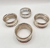 Group shot of four napkin rings, three with ruffled edges, one pierced sterling
