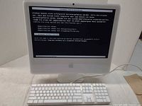 Front view of white Apple iMac booted to Windows error screen with Apple keyboard