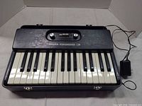 Full view of Hohner Bass 3 keyboard in open hard case with power adapter