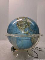 Full view of illuminated National Geographic globe on clear base with power cord