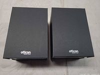 Two closed black Oticon boxes