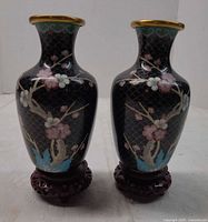 Front view of both cloisonné vases on stands showing floral design and black background