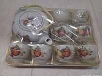 Top view of packaged tea set showing teapot, eight cups and tray