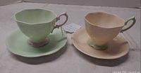 Two teacups with matching saucers, green and peach