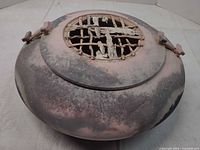 Angled view of vessel showing overall form, colors, lid lattice damage