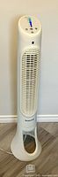 Full view of Honeywell tower fan standing on floor, power cord visible, remote in foreground