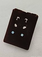 Front view of two earring pairs on velvet card