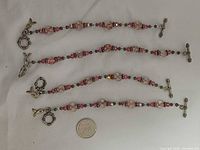 Three bracelets laid flat beside a coin for scale