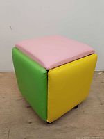 Cube ottoman showing green and yellow sides with pink top