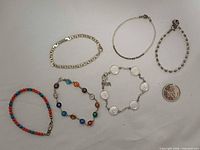 All six sterling silver bracelets with coin for scale