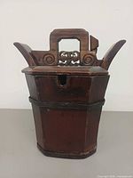 Front view of wooden container showing lid and carved handle