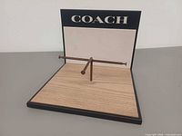 Front view showing base, metal rod, Coach logo on back panel