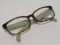 Oblique view of Prada eyeglasses showing tortoise front and green temples