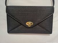 Front view showing woven texture, envelope flap, gold turn-lock