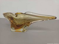Side profile showing elongated freeform amber glass bowl with clear base
