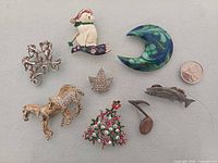 Full group of eight costume brooches with coin for scale
