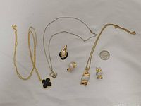Group overview of four necklaces, pair of earrings, and scale coin