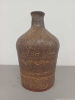 Front view of brown speckled pottery vase with geometric incised pattern