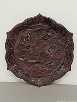 Front view of entire carved plate showing scalloped rim and overall design