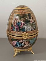 Front view of hand-painted porcelain egg on gilt stand