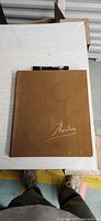 Front cover showing tan cloth boards, gilt signature, circular stain