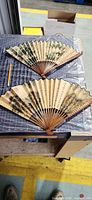 Both folding fans opened showing painted sides