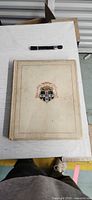 Front cover with coat of arms, cream cloth, visible soiling