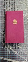 Front cover showing magenta cloth board with gilt emblem