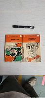 Front covers of both Penguin paperbacks with marker for scale