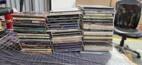 Two stacks of roughly 35 jewel-case CDs on cutting mat