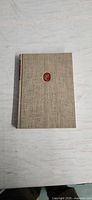 Front cover showing beige linen cloth and red medallion