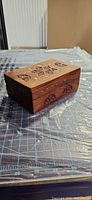 Angled view of wooden jewelry box showing carved sides and lid