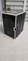 Box set standing showing six book spines inside white-edged slipcase