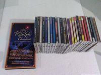 Group shot of 25 individual CDs aligned beside A Very Rudolph Christmas box