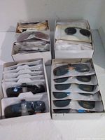 Four boxes filled with rows of individually packaged clip-on sunglasses