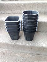 Stack of four square pots beside stack of eight round pots on concrete step
