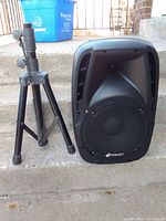 Front view of Sonart EP23880 PA speaker beside folded tripod stand