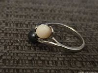 Top view of white gold ring showing white and black pearls