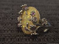 Front view of sterling silver ring showing yellow opalescent cabochon and floral vine with pink stones