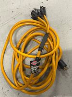 Coiled yellow generator cord with connectors and label